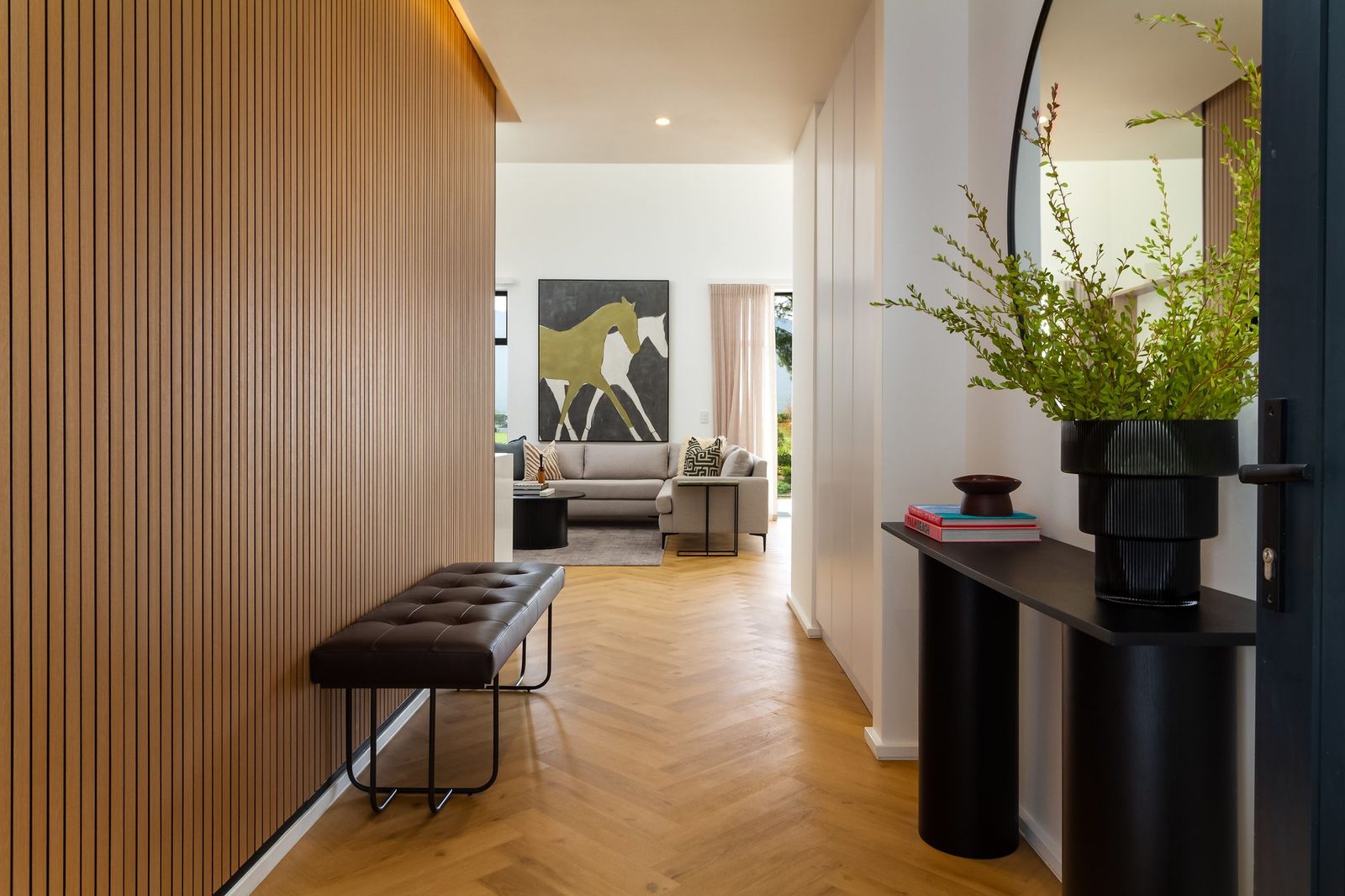 Val de Vie: entrance hall with fluted oak panelling, a leather bench and a herringbone floor
